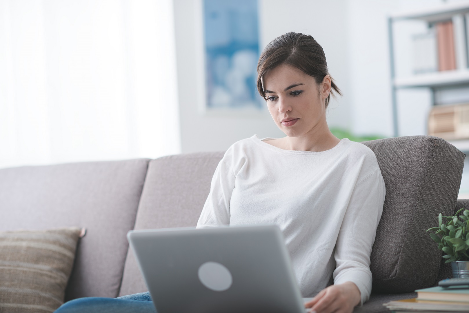 Young attractive woman relaxing on the sofa at home and connecting to the internet with a laptop